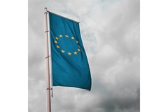 Image The EU flag flying in the wind in front of gray clouds.